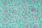 Close-up of blue lotus flower buds and delicate vine motifs on aqua block printed cotton fabric