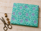 Folded aqua hand block printed cotton fabric with blue lotus buds and trailing vine pattern