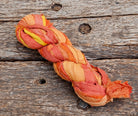 Single skein of Sunset Mango sari silk ribbon featuring orange, peach and golden yellow tones.