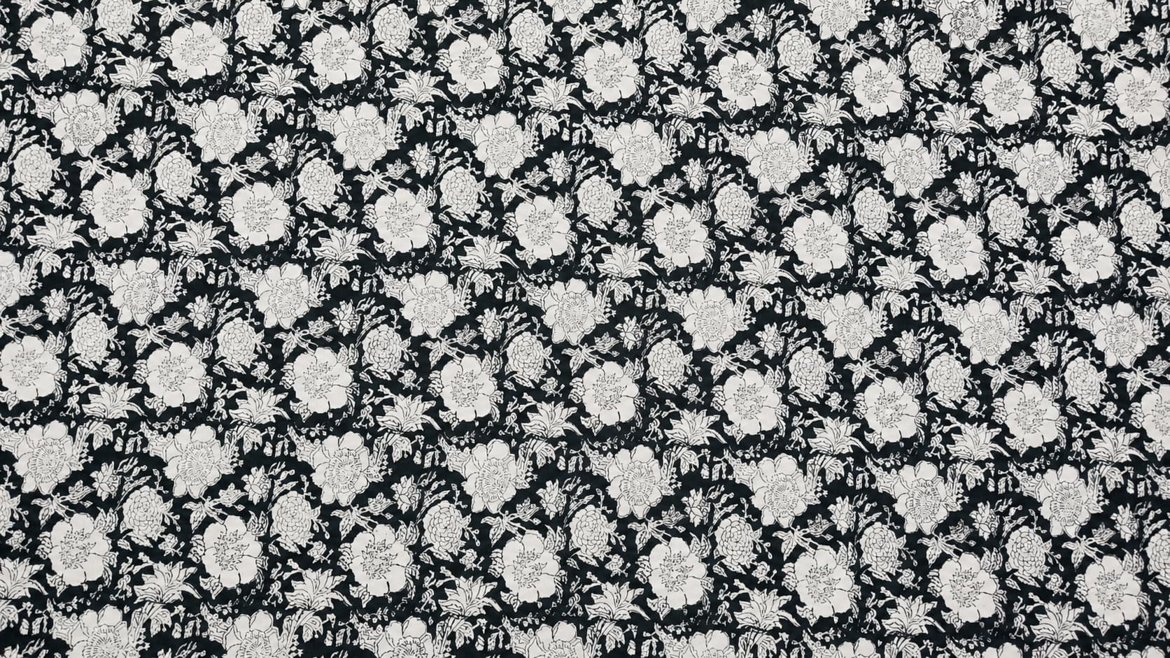 Black and white botanical block printed cotton fabric with detailed floral motifs