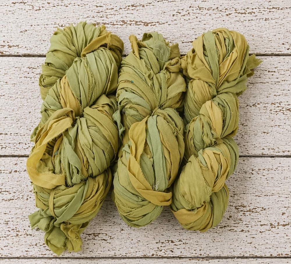 Multiple skeins of olive moss chiffon silk ribbon yarn arranged together