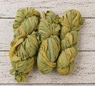 Multiple skeins of olive moss chiffon silk ribbon yarn arranged together
