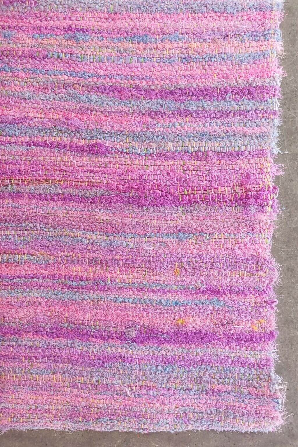 Full view of handwoven sari ribbon fabric in pastel pink and lilac tones made from reclaimed sari silk ribbons.