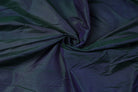 Peacock Blue Dupion Silk Fabric arranged in elegant swirling folds highlighting its colour-shifting sheen and rich peacock-inspired tones