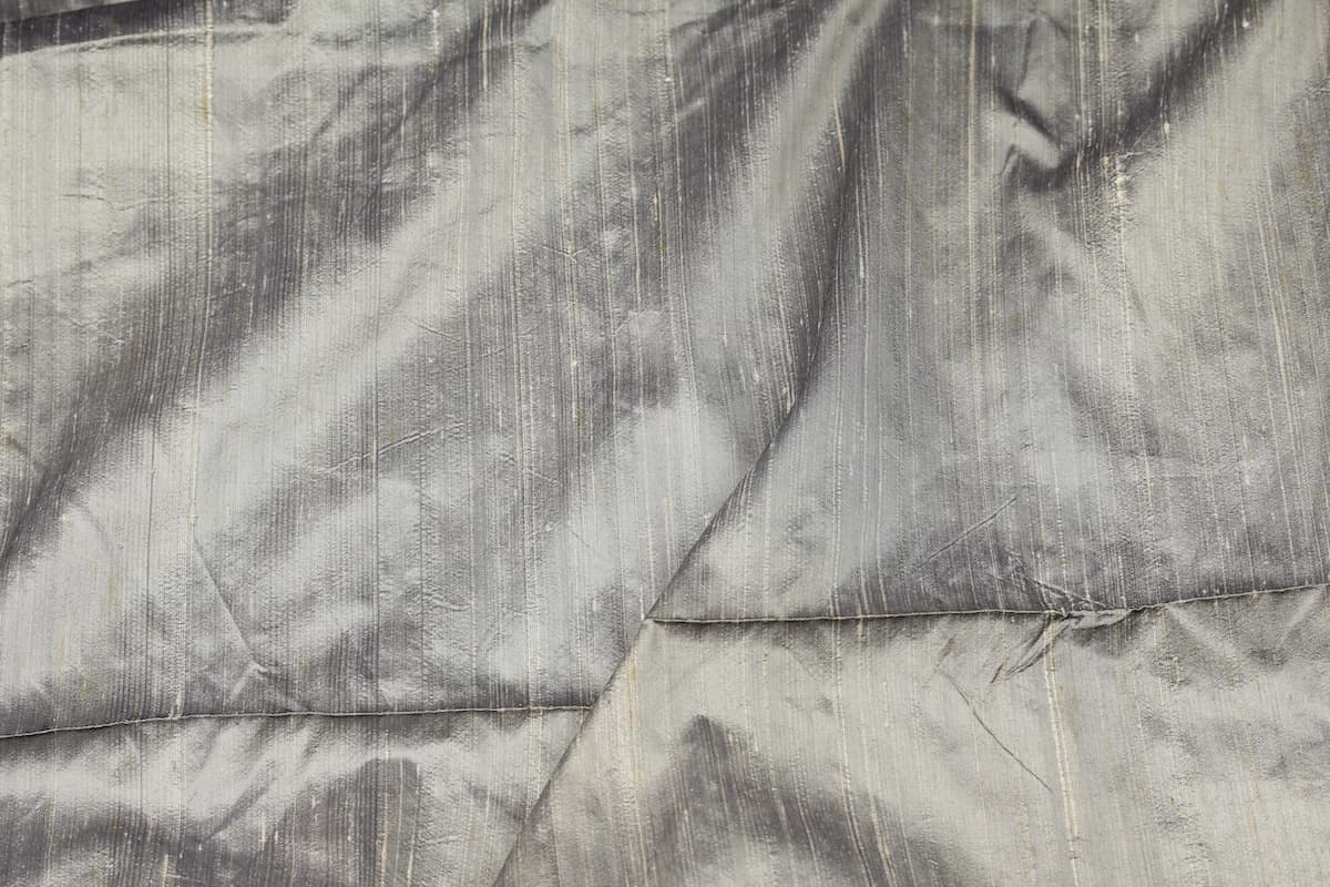 Silver Pewter dupion silk fabric draped to display metallic silver finish, natural slubs, and textured raw silk weave