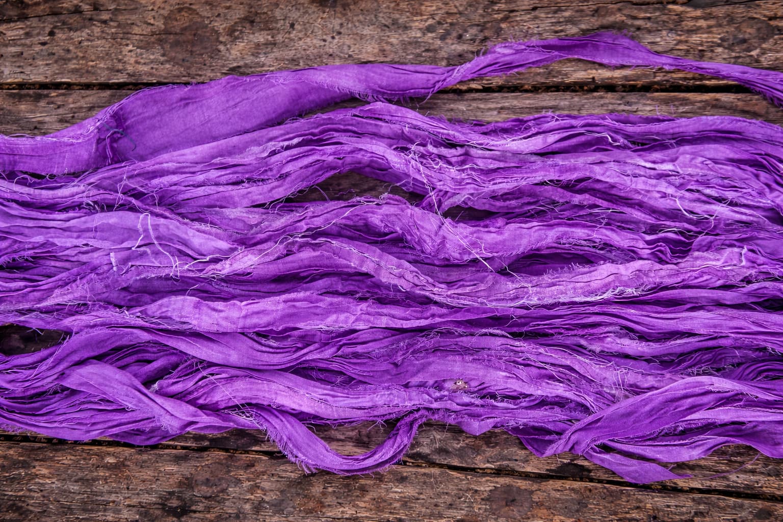 Long length of violet sari silk ribbon displaying rich colour and soft texture.
