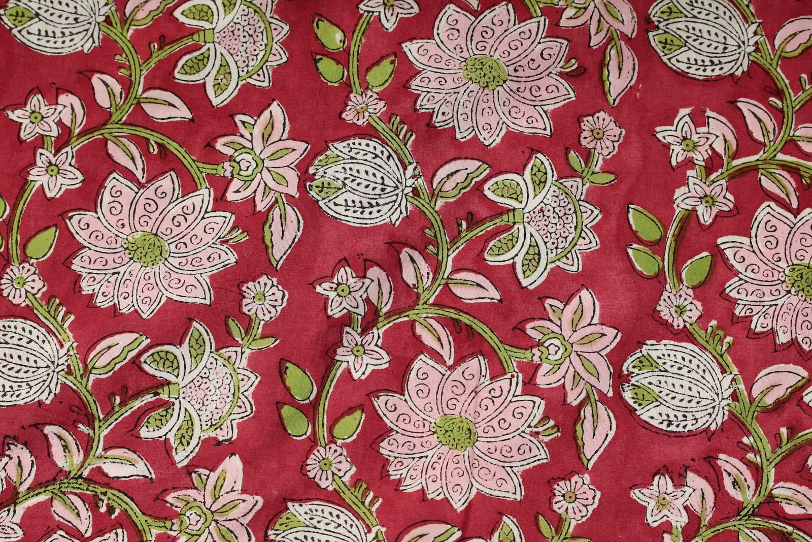 Close-up of Raspberry Lotus Vine block printed cotton fabric showing pink lotus flowers, green vines, and hand-printed details