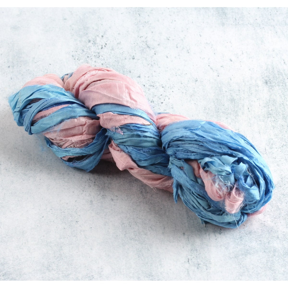 Pastel pink and sky blue sari silk ribbon skein on white background,  perfect for crafts and DIY projects.