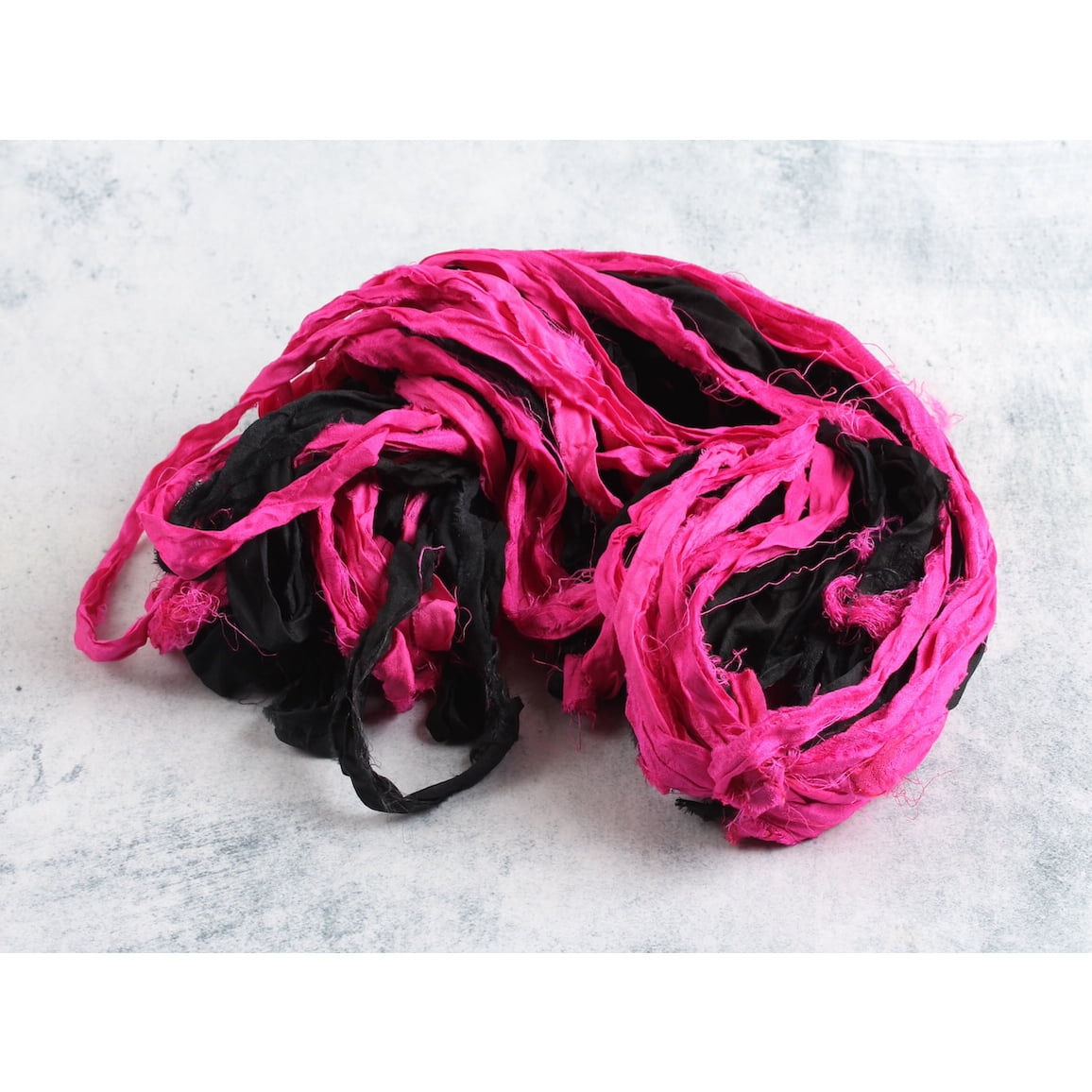Pop pink and black sari silk ribbon opened to show vibrant color mix and texture
