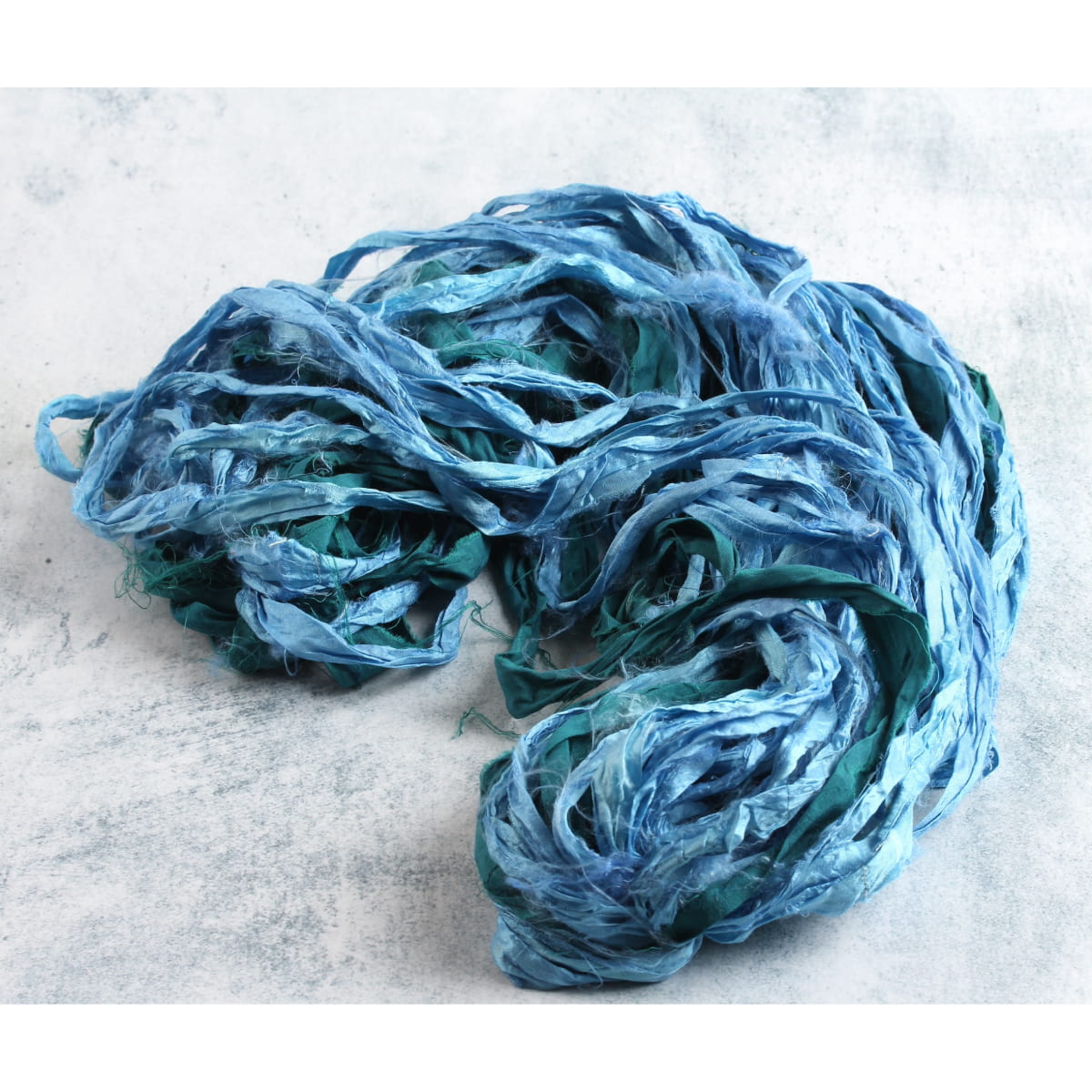 Sky blue and teal sari silk ribbon displayed open to show texture, color mix, and handmade frayed edges, ideal for sewing and crafts.