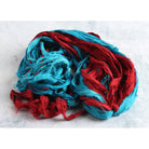Open view of turquoise and red sari silk ribbon showing hand-dyed colors and frayed edges.
