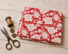 Folded scarlet red hand block printed cotton fabric with ivory floral blossom pattern