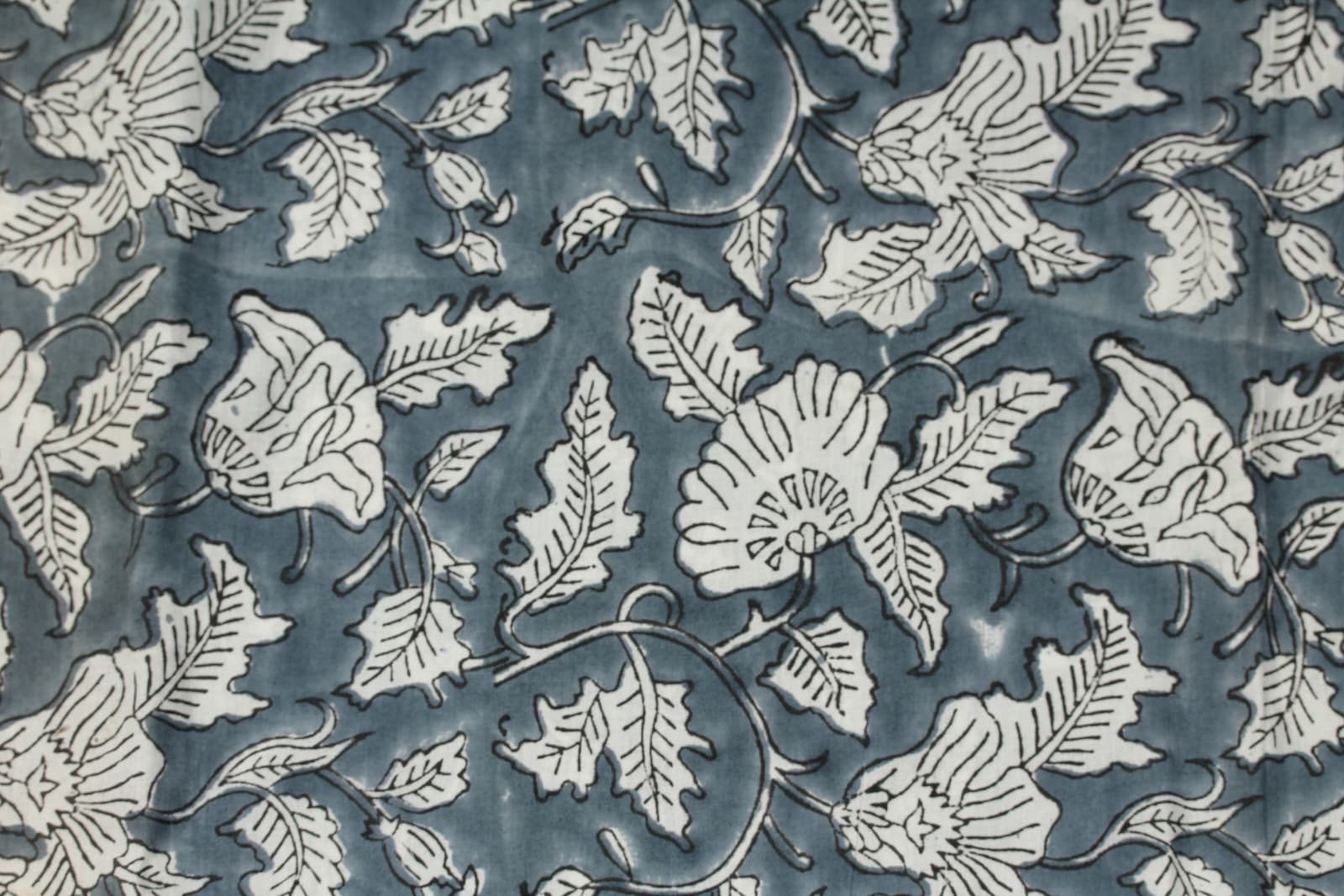 Close-up of Slate Meadow Bloom block printed cotton fabric showing ivory flowers, leaves, and trailing vine details