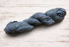Single storm grey sari silk ribbon skein in a muted grey shade.