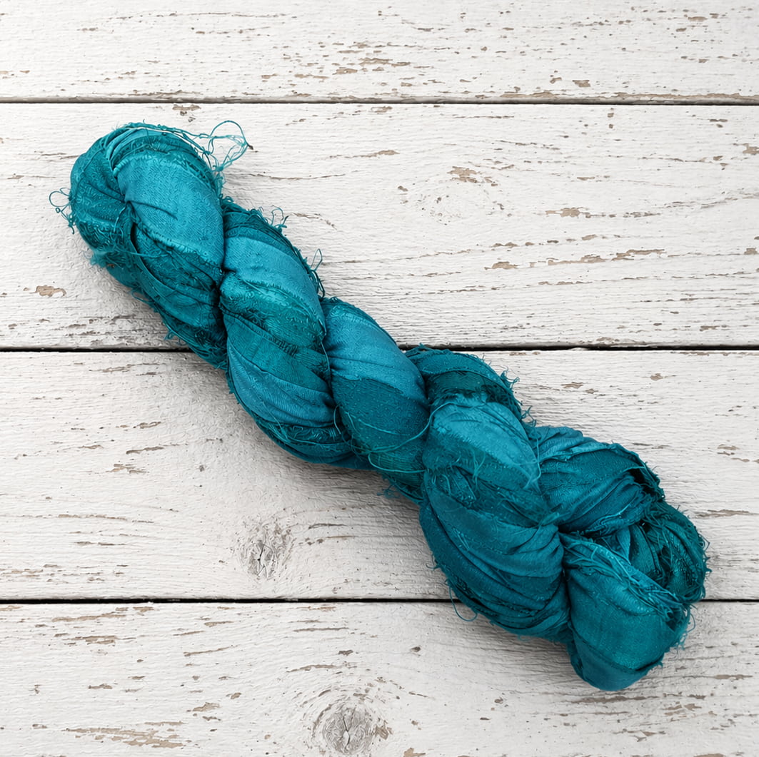 Single skein of Peacock Lagoon sari silk ribbon yarn in deep teal blue