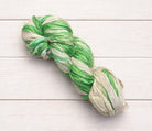 Variegated green and ivory sari silk ribbon yarn skein on white wood background