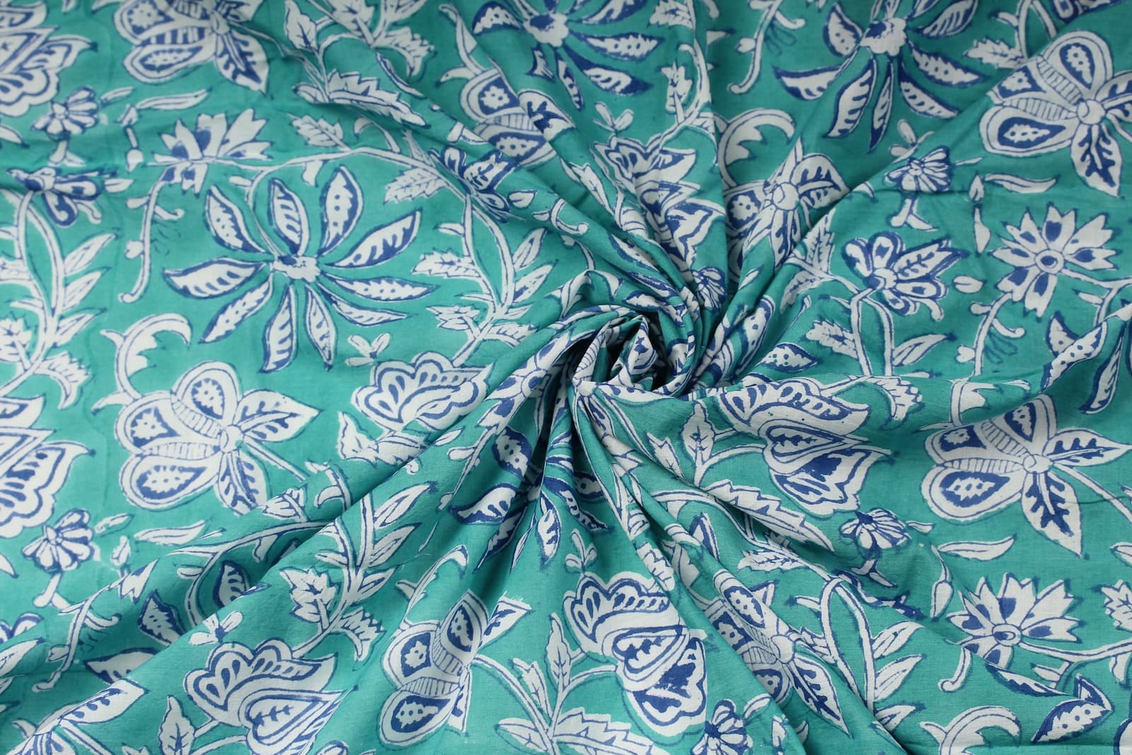 Turquoise hand block printed cotton fabric gathered to display drape and floral botanical design