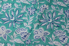 Close-up of turquoise floral block print cotton fabric featuring indigo blossoms, vines, and botanical motifs