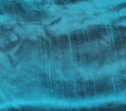 Close-up of Turquoise Blue Dupion Silk Fabric showing natural slub texture, woven silk character, and shimmering aqua-blue finish