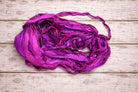 Loose hank of Wild Orchid sari silk ribbon displaying flowing strands of recycled silk.